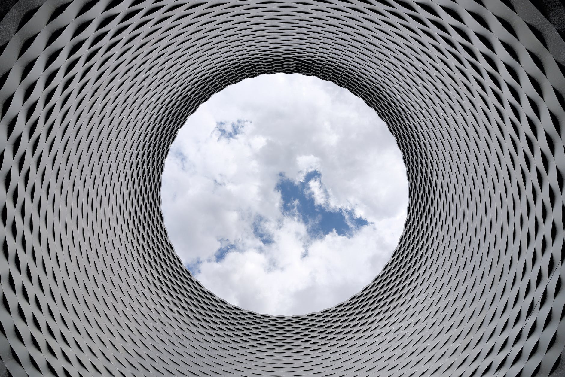 low angle photography of grey and black tunnel overlooking white cloudy and blue sky